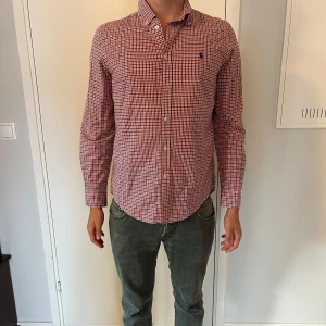 Skjorta från polo ralph lauren - Snygg rutig skjorta från Ralph Lauren i storlek XL. Skjortan har klassiskt röd, blå och vit rutmönster, lång ärm och knappar framtill. Tillverkad i mjuk bomull och har den ikoniska broderade loggan på bröstet. Perfekt för en clean och stilren look.