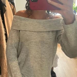 Grå offshoulder stickad tröja H&M - Supermjuk ljusgrå stickad tröja från H&M med bred offshoulder-krage som kan stylas på olika sätt. 