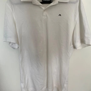 Vit pikétröja från J.Lindeberg - Klassisk vit pikétröja från J.Lindeberg med liten broderad logga på bröstet. Perfekt till lite varmare väder. Är knappt använd. Storlek S.