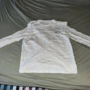 Vit långärmad tröja Polo Ralph Lauren - Vit långärmad tröja från Polo Ralph Lauren i storlek M. Klassisk och clean design med liten broderad logga på bröstet. Tillverkad i mjuk bomull som är skön mot huden. Perfekt för en stilren och avslappnad look.