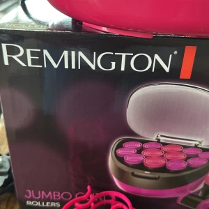 Remington Jumbo Hårspolar - Säljer ett set Remington Jumbo Rollers med 12 stora värmespolar i rosa och lila plast. Medföljer matchande klämmor och metallnålar för att fästa spolarna. Perfekt för att skapa stora, voluminösa lockar snabbt och enkelt hemma.