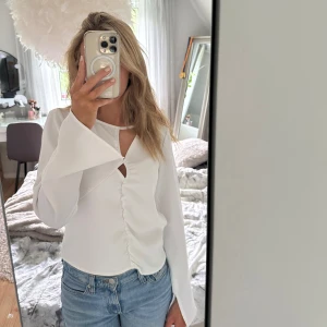 Vit blus med utsvängda ärmar BikBok - Supersnygg vit blus från BikBok i storlek XS. Blusen har långa utsvängda ärmar, unik cut-out detalj framtill och lätt rynkad söm längs mitten. Tunt material, endast använd ett fåtal gånger, 100kr+frakt!