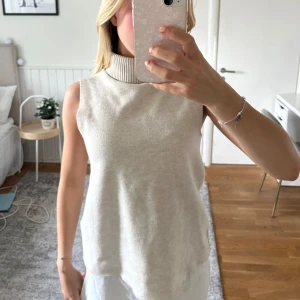 Beige tröja  med polokrage - Säljer en beige tröja från ZARA med hög ribbad polokrage. Västen är ärmlös och har en rak, något loose passform. Perfekt att styla över en skjorta eller långärmad tröja för en trendig lager-på-lager-look.