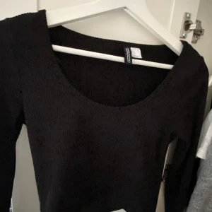 Svart stickad tröja från hm - Säljer en svart stickad tröja från hm med rundad, djup ringning och långa ärmar. Perfekt att matcha med jeans eller kjol för en stilren look. Tröjan har en klassisk passform och är supermjuk.