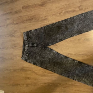 Svarta acid wash jeans galaxy fit WEEKDAY - Säljer ett par svarta Galaxy acid wash jeans från Weekday med baggy passform och klassisk femficksdesign. Jeansen kan bäras hög och lågmidjat. Snyggt slitna detaljer och cool vintagekänsla. Perfekta till sneakers eller boots. STORLEK 30/32.