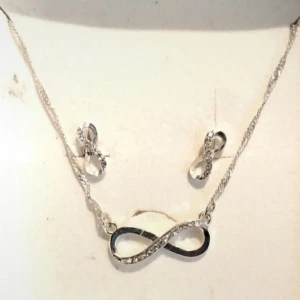 Silverset med evighetssymbol - Snyggt smyckeset med halsband och örhängen i silverfärg, båda med glittrande evighetssymboler dekorerade med små stenar. Perfekt för dig som gillar stilrena och trendiga accessoarer med en touch av bling.