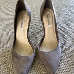Grå mocka pumps från NLY Shoes / storlek 38 - Snygga grå pumps i mocka från NLY Shoes med spetsig tå och hög klack på ca 10 cm. Klassisk och stilren modell som ger en elegant look. Perfekta för dig som vill ha en tidlös sko med modern känsla.