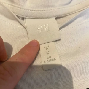 Vit t-shirt med tryck från H&M - Vit t-shirt från H&M i bomull med coolt färgglatt tryck på framsidan och texten 'Mi casa es su casa'. Klassisk passform med korta ärmar och rund hals. Perfekt för dig som gillar unika prints och chill vibe.