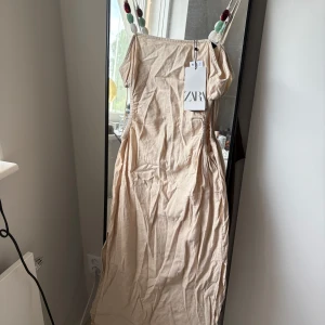 Beige klänning från Zara - Superfin beige långklänning från Zara med öppna sidor. Nypris 359kr säljs för 100kr