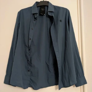 Skjorta från G-Star RAW Correctline - Härlig snygg skjorta från G-Star RAW Correctline med knappar framtill och lång ärm. Skjortan är tillverkad i bomullsblandning med stretch och har en stilren look med liten logga på bröstet. Perfekt för dig som gillar enkel och modern stil. Riktigt snygg färg, typ mörk turkos. 
