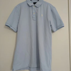 Ljusblå pikétröja från G-Star RAW - Oanvänd! Säljer en stilren ljusblå pikétröja från G-Star RAW i storlek S. Tröjan har klassisk krage, knäppning med tre knappar och diskret logga på bröstet. Tillverkad i ekologisk bomull och har korta ärmar. Perfekt för en clean och avslappnad look. En