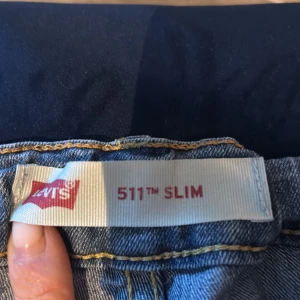 Levi's 511 Slim ljusblå jeans - Säljer ett par Levi's 511 Slim jeans i ljusblå tvätt. Klassisk femficksmodell med smal passform och normal midja. Jeansen har snygga slitningar och är tillverkade i mjukt denimtyg. Perfekta för en avslappnad och stilren look.