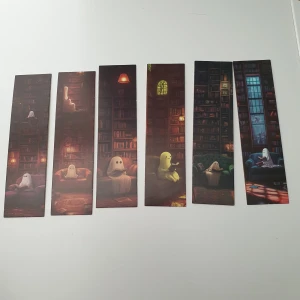 6st Spökiga bokmärken i biblioteket - Ett set med sex bokmärken som visar söta spöken som läser böcker i mysiga biblioteksmiljöer. Perfekt för dig som älskar böcker, fantasy och vill ha en unik touch till din läsning. Passar både ungdomar och unga vuxna som vill göra läsningen lite roligare. Skick: oanvända, men verkar som färger har gått över lite från ena bokmärken till den andra baksida. Så är lite fläckigt.