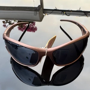 NYA Bruna sportiga solglasögon - NYA Snygga solglasögon med brun  båge. Modellen har en sportig, svepande form som ger en cool look och bra täckning mot solen. Hämtas på Hägerstensåsen. 