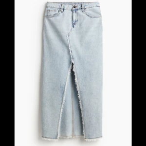 Ljusblå jeanskjol med slits - Säljer en lång ljusblå jeanskjol med fransiga kanter och en snygg slits framtill. 