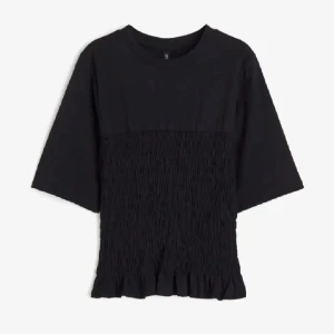 Svart topp med smock och volang - Svart topp med smockad midja och volangkant nertill. Modellen har rund halsringning och halvlånga ärmar. Perfekt för dig som gillar en enkel men ändå trendig look. Pris kan diskuteras 💓