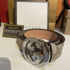 Beige bälte med silverfärgat spänne - Snyggt beige bälte med ett stort, runt silverfärgat spänne. Perfekt för att ge en stilren touch till din outfit. Bältet har en slät yta och en justerbar rem. Gu€€i med kvitto kom dm för mer bilder!