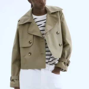 Kort beige trenchcoat från hm - Snygg kort trenchcoat i beige med knappar. Perfekt för dig som gillar stilrena och trendiga plagg med klassisk touch. 