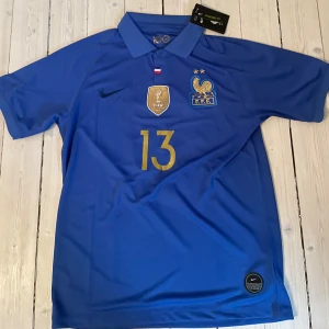 Frankrike Kante 13 fotbollströja Nike - Snygg Frankrike fotbollströja från Nike med nummer 13 och Kante på ryggen. Endast provad och säljer den då den tyvärr inte passa. 