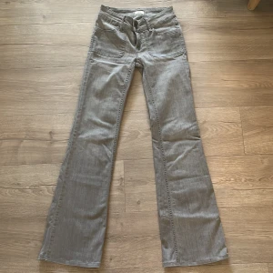 Trendiga ljus grå lågmidjade bootcut jeans med fickor - Trendiga, snygga grå jeans med bootcut passform med framfickor. Byxorna har även bakfickor med knapp. 