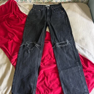 Svarta ripped jeans från g perfect jeans - Svarta jeans från g perfect jeans i rak modell med slitna hål över knäna för en edgy look. Klassisk femficksdesign och knappgylf. Jeansen har en mörk tvätt och är tillverkade i kraftigt denimtyg.