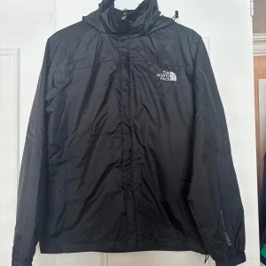 The North Face Vindjacka - Svart vindjacka från The North Face Summit Series i storlek L. Jackan har huva, dragkedja framtill och elastiska muddar. Snygg och stilren design med logga på bröstet och ärmen. Jackan är lätt fodrad. Den är liten i storleken så passar den som har M/S i storlek. Skriv vid frågor 🤩