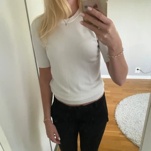 Vit stickad topp från Zara - Vit, stilren stickad topp från Zara med rund halsringning och korta ärmar. Sitter snyggt och har en lätt croppad passform. Perfekt till både jeans och kjol för en clean look. Materialet är mjukt och stretchigt för extra komfort.