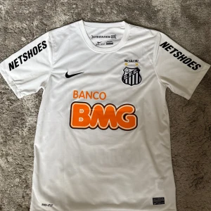 Santos FC tröja – Neymar Jr #11 (2012) - Officiell hemmatröja från jubileumssäsongen 2012, då Santos firade 100 år. Neymar Jr med nummer 11 på ryggen, originaltryck. 🔸 Märke: Nike (Dri-FIT) 🔸 Skick: Mycket bra 🔸 Sponsorer: BMG, Netshoes 🔸 Autentisk etikett och jubileumsdetaljer  Perfekt för samlare eller Neymar-fans!