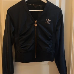 Svart Adidas jacka/kofta - Adidas kofta/jacka köpt för länge sen men endast används ett fåtal gånger. Denna säljs inte längre och har inga tecken på skador. Står storlek 40 men passar mig med S-36 perfekt. Säljer pga att den inte kommer till användning. Den är köpt för ca 700kr