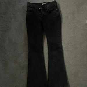 Gråa  bootcut jeans  - Säljer ett par mörkgråa bootcut jeans. Jeansen har klassisk femficksdesign och är i stretchigt denimtyg som sitter snyggt över höfterna och släpper ut vid benen. Perfekta om du gillar en retro vibe och vill ha en cool siluett.