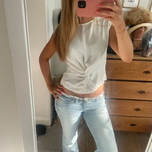Vit ärmlös omlottopp - Snygg vit ärmlös topp med omlottdetalj framtill. Tunt och lätt material. Perfekt på finare tillfällen eller bara i vardagen! Pris kan diskuteras!