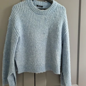 Ljusblå stickad tröja från Gina Tricot - Supermysig ljusblå stickad tröja från Gina Tricot med grov ribbstickning och rund hals. Tröjan har långa ärmar och slits vid ärmen. Perfekt nu till hösten! Avnvänd få gånger och sticks inte. 