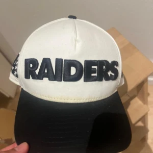 Raiders keps från New Era 9FIFTY - Snygg Raiders snapback-keps från New Era 9FIFTY med broderad logga framtill och bak. Kepsen är vit med svart skärm och detaljer, justerbar baktill och tillverkad i bomull. Perfekt för dig som vill ha sportig stil och visa ditt NFL-support.