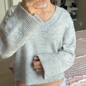 Grå stickad tröja  - Mysig ljusgrå stickad tröja från Gina Tricot med breda ribbade muddar och v-ringad hals. Den är så gott som ny (ej noppig eller andra defekter) och har bara används 3 ggr!! Skriv för fler bilder eller eventuella frågor❣️❣️