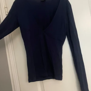 Mörkblå långärmad v-ringad tröja - Snygg mörkblå långärmad tröja med djup v-ringning framtill. Modellen är slim och sitter tajt mot kroppen, perfekt för dig som gillar en stilren och enkel look. Materialet känns mjukt och lätt, passar bra till jeans eller kjol. Storlek Xs/S, säljer för att den var för stor, aldrig använd. Varan säljs på flera plattformar💕