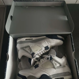 Nike Air Jordan 4 White Oreo sneakers - Nike Air Jordan 4 sneakers i vitt skinn med grå och marinblå detaljer. perfekt för dig som vill sticka ut med en ikonisk sneaker. Storlek 43. Om du har några funderingar så är det bara att fråga.
