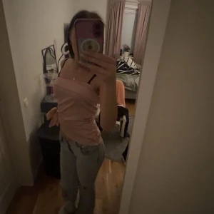 Ljusrosa tubtopp från SHEIN - Säljer en ljusrosa tubtopp från SHEIN i storlek S. Toppen är axelbandslös och har en snygg knytdetalj på sidan. Materialet är mjukt och har en lätt glansig finish som ger en fräsch look. Perfekt att styla med jeans eller kjol för en trendig vibe.