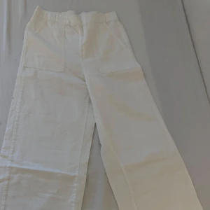 Vita linnebyxor med fickor - Snygga vita linnebyxor med elastisk midja och stora framfickor. Perfekta för en avslappnad stil med en luftig känsla. Byxorna har en rak passform och är tillverkade i ett lätt och bekvämt material.