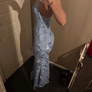 Ljusblå långklänning med blommigt mönster - Elegant ljusblå långklänning med blommigt mönster och smala axelband. Klänningen har en tight passform och är perfekt för speciella tillfällen. Köptes för 1200kr ink tull osv… Säljer för 900kr❤️ Kvitto kan skickas privat!