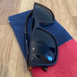 Solglasögon från Le Specs - Snygga solglasögon från Le Specs med en klassisk rektangulär form. Bågarna har en mörk sköldpaddsmönstrad design och glasen är mörkt tonade. Perfekta för soliga dagar!