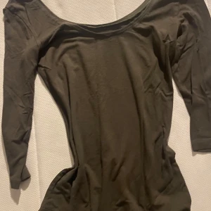 Olivgrön långärmad topp - Säljer en olivgrön långärmad topp med en bred halsringning. Perfekt för lager-på-lager eller som den är. Passar till både jeans och kjol.