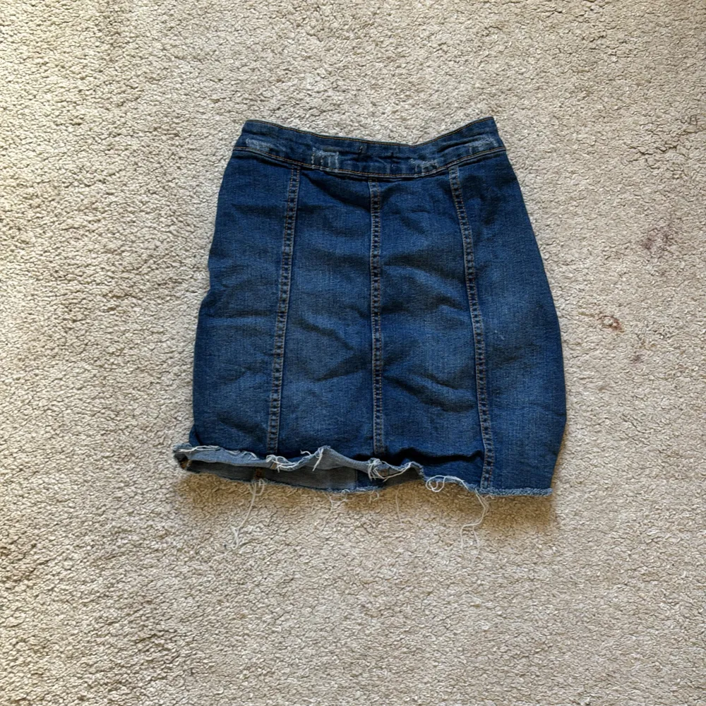 Snygg jeanskjol i blå denim med knappar framtill. . Hameet.