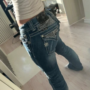 Miss Me jeans med strassdetaljer - Ett par blå Miss Me jeans med snygga slitningar och strassdetaljer där bak och på fickorna🌟Storlek 29, sitter bra på mig som är en ca 36/38 och fin längd för mig som är 167 cm, men passar även på lite längre!