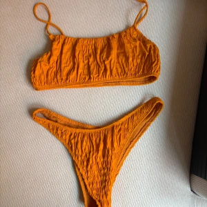 Orange bikini från Nelly - Orange bikini från Nelly med en ribbad textur. Toppen har smala axelband och en enkel design och underdelen har en hög midja. 