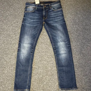 Mörkblå Nudie jeans (Oanvända) - Tja! Säljer nu ett par snygga mörkblå jeans från Nudie med en klassisk femficksdesign. De har en lätt tvättad look med subtila slitningar och kontrastsömmar. Perfekta för en avslappnad stil. Helt nya och aldrig anvönda eftersom att de var för små för mig. Inga defecter//Slim fit//Thin finn//W31 L30//Ny pris 1599 kr