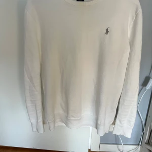 Vit tröja från Polo Ralph Lauren - Säljer en stilren vit tröja från Polo Ralph Lauren i slim fit. Tröjan har långa ärmar och ett diskret logotypbroderi på bröstet. Perfekt för en klassisk och elegant look.