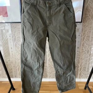  Carhartt carpenter pants green size w36l32 - Säljer ett par gröna byxor från Carhartt i 100% bomull. Byxorna har en avslappnad passform med flera praktiska fickor och en klassisk design. Perfekta för en casual look. 