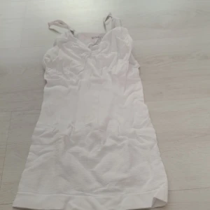 Vitt linne  med axelband shaping Large - Säljer ett vitt  linne med axelband. Linnet har en shaping effekt när man vill se smalare ut Storlek Large