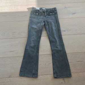 Grå jeansbyxor från Gina Tricot - Snygga grå jeansbyxor från Gina Tricot med bootcut-stil. Byxorna har klassiska femficksdetaljer och bälteshällor. Perfekta för en avslappnad look.