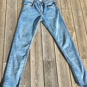 Snygga blå jeans från Replay Hyperflex med en klassisk femficksdesign. De har en knappgylf och är tillverkade i ett stretchigt material för extra komfort. Perfekta för en avslappnad stil.